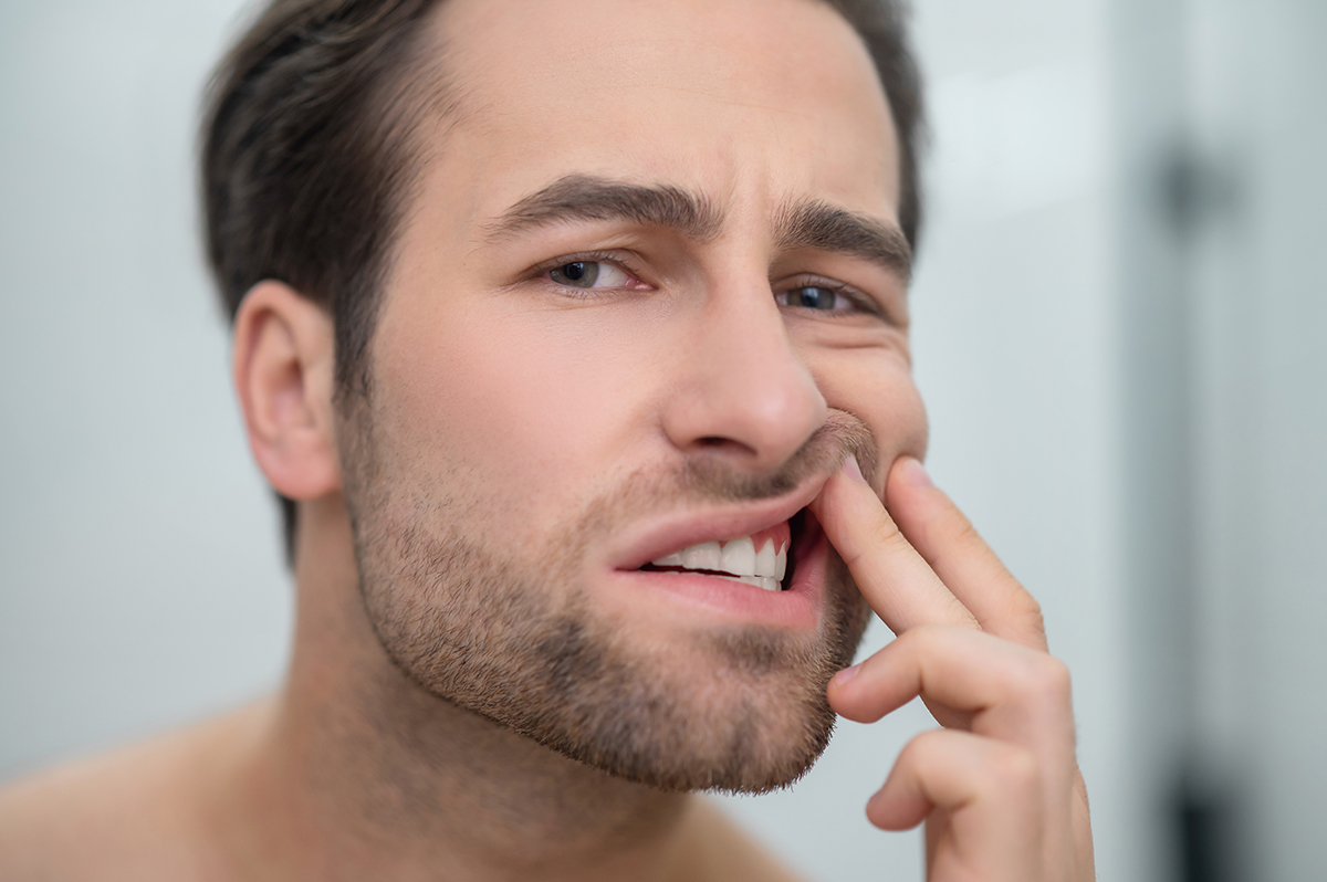 Dental problems man checking his teeth looking disturbed