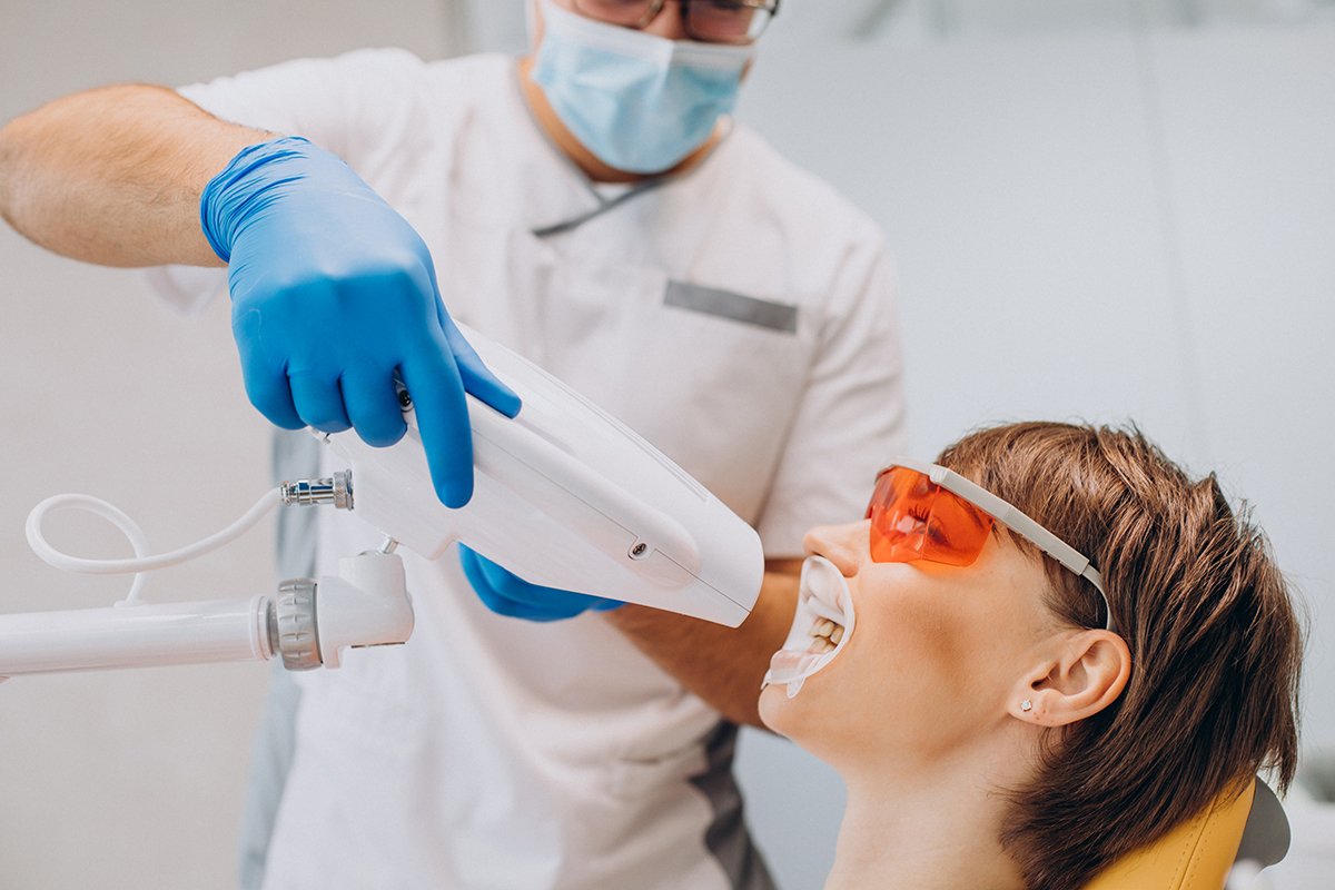 Woman whitening teeth dentistry with special equipment